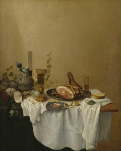 Still life with stoneware jug, bekerschroef, glassware and a leg of ham by Gerrit van Vucht
