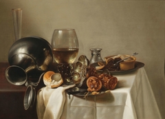 Banquet still life with a rummer of wine, a toppled-over pewter jug, precious vessels, a pastry and a roll