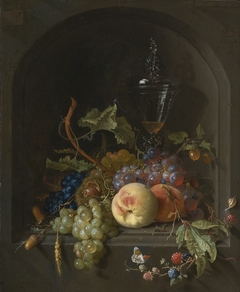 Still life of grapes, peaches, blackberries, acorns, prickly fruit, an elaborate glass and various insects on a ledge in a niche