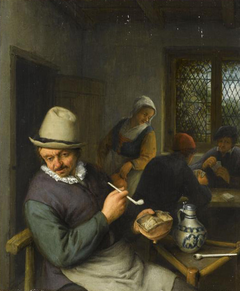 A tavern interior with a peasant smoking a pipe and figures playing cards
